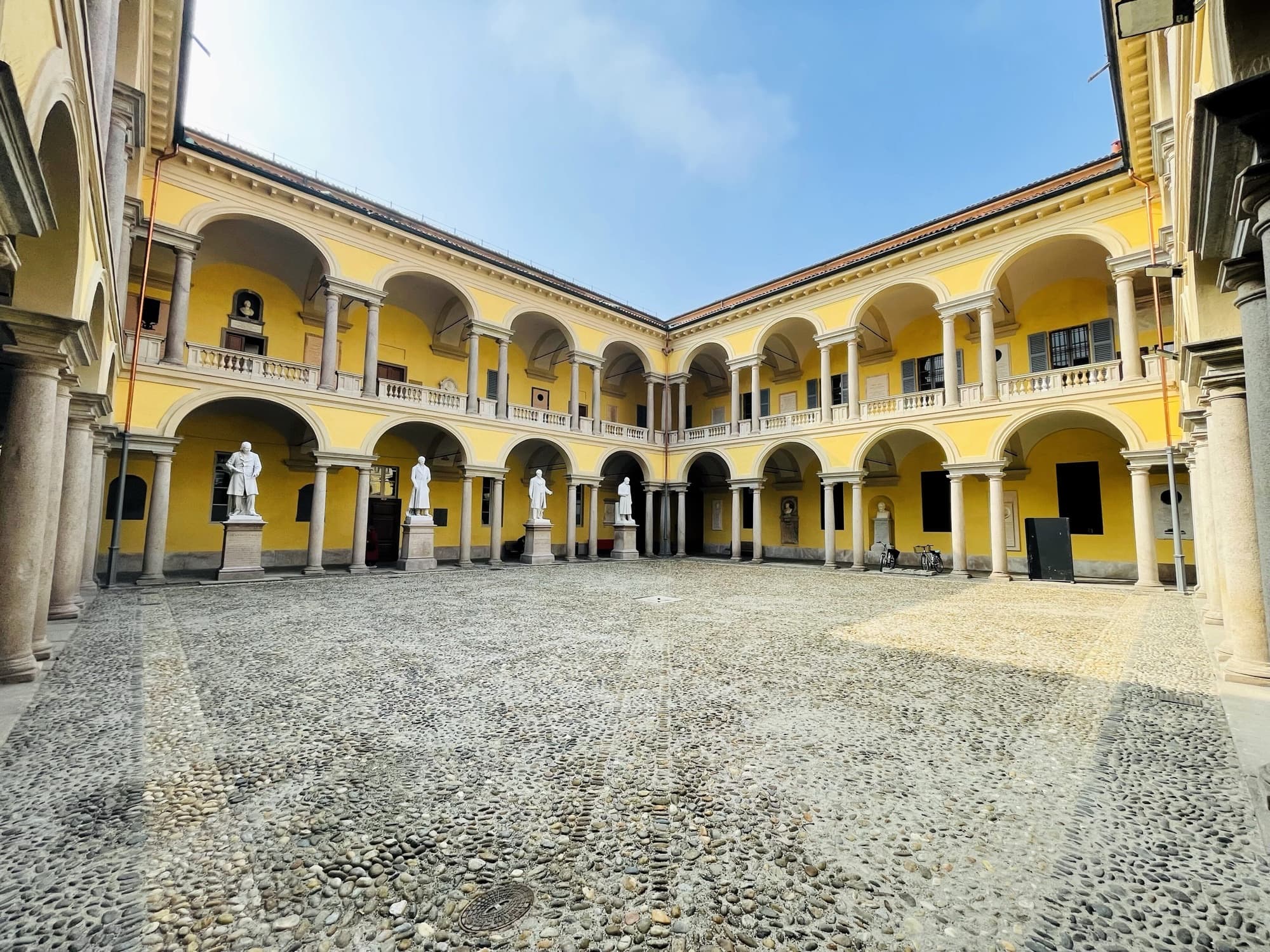 Il cortile delle statue dell'Università di Pavia, con le logge gialle su due piani e le statue dei professori